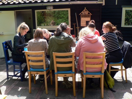 Groep pabostudenten in tuin van De Lange akker aan het werk aan grote tafel